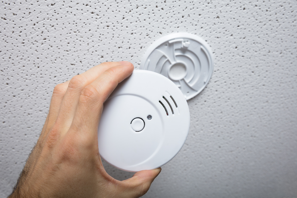 Person,repairing,the,smoke,detector,on,the,ceiling,wall