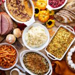 Thanksgiving,table,with,roasted,turkey,,sliced,ham,and,side,dishes