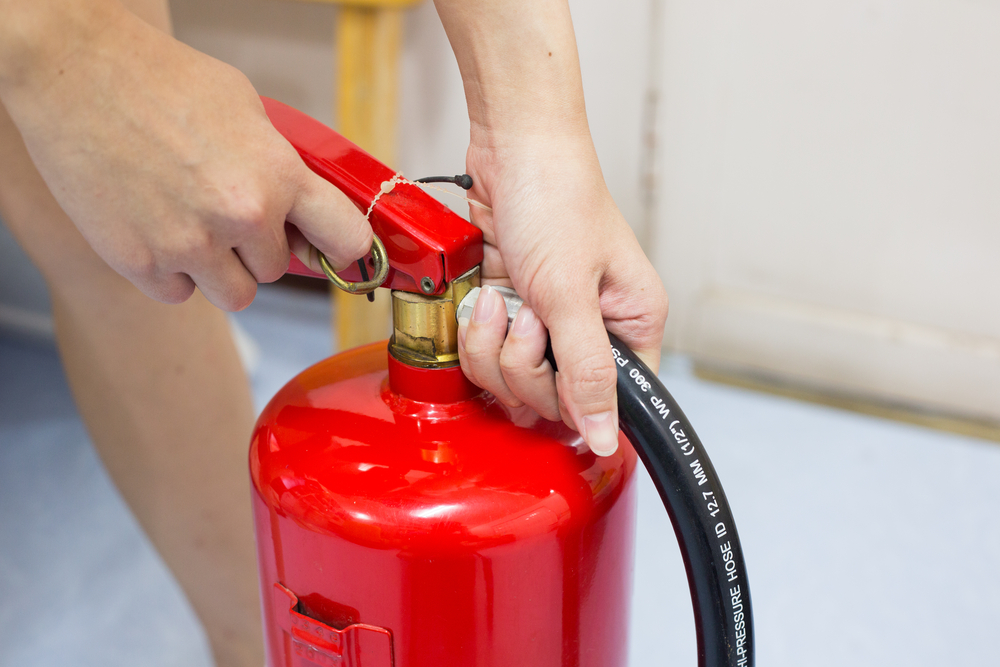 Close ,up,fire,extinguisher,and,pulling,pin,on,red,tank.